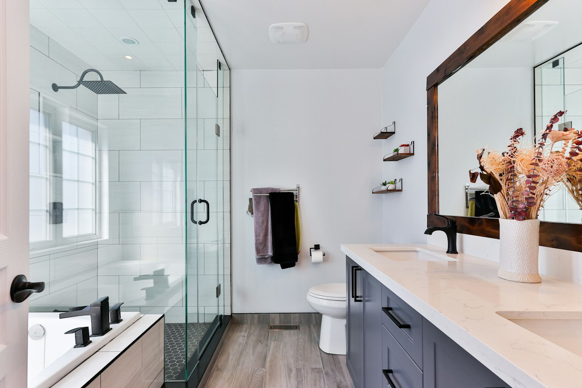 Bright renovated bathroom with timber vanity, black tapware and glass shower
