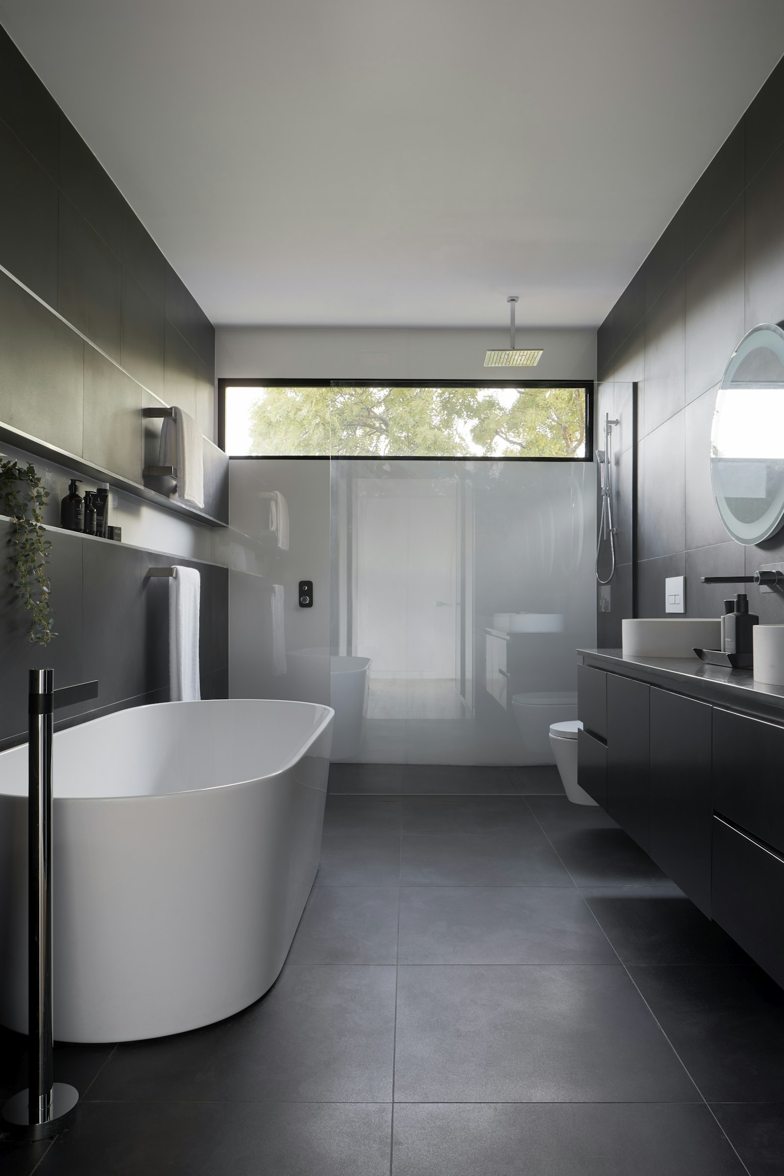 Luxurious renovated bathroom with freestanding bath and dark stone-look tiles
