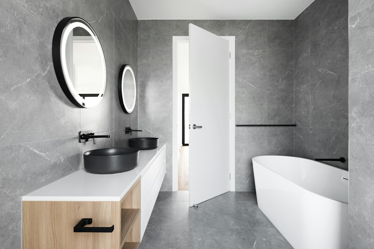 Contemporary bathroom with grey stone-look walls, vessel basin and round mirror