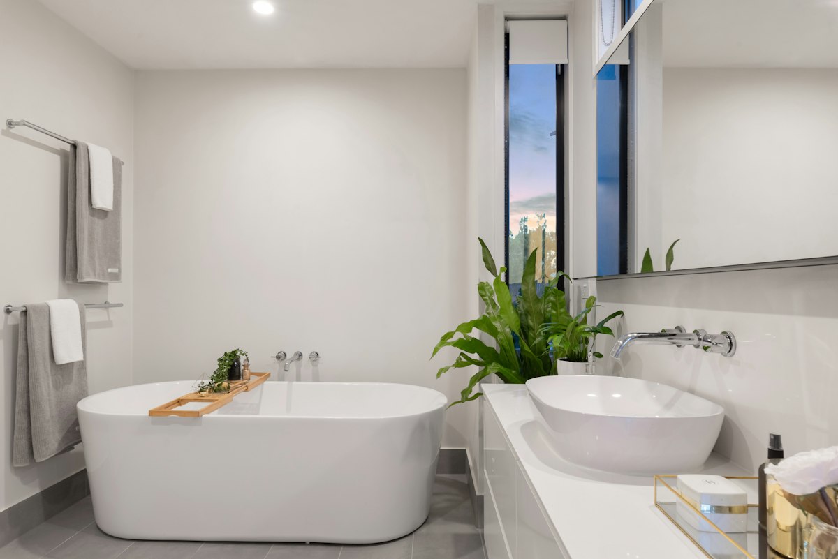 Bright renovated bathroom with white freestanding bath and indoor plants
