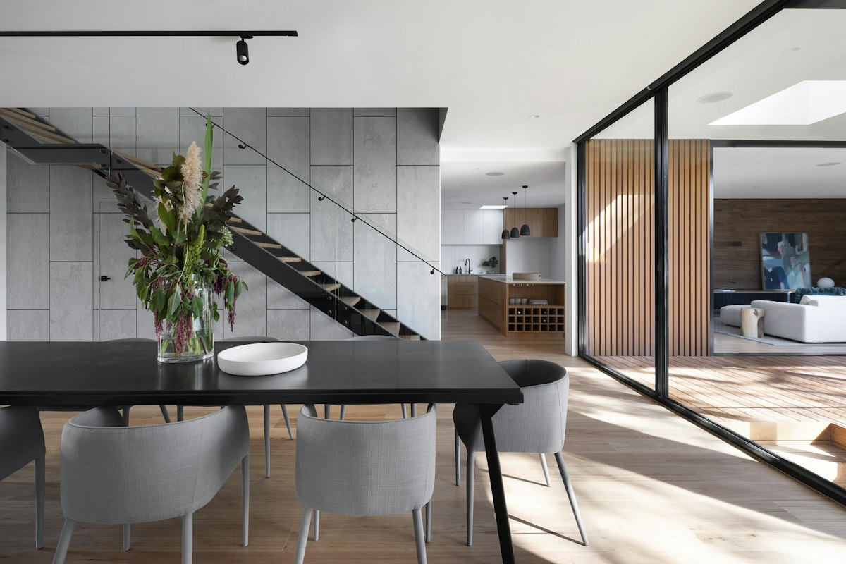 Open-plan extension interior with steel staircase, timber joinery and dining area