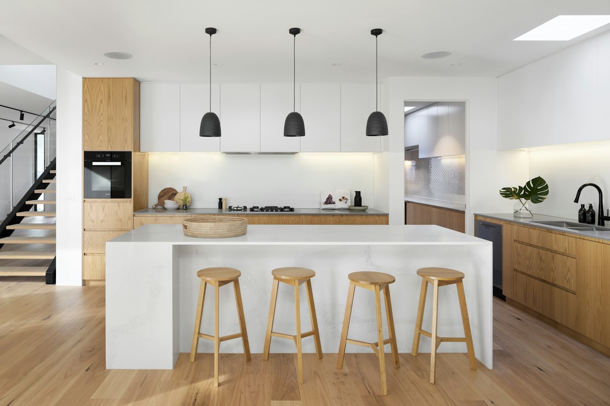 Kitchen island with timber stools and pendant lighting in a renovated open-plan space