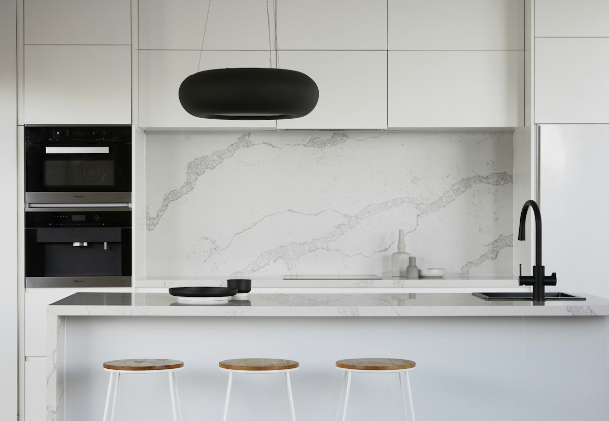 White marble kitchen with island bench and timber stools